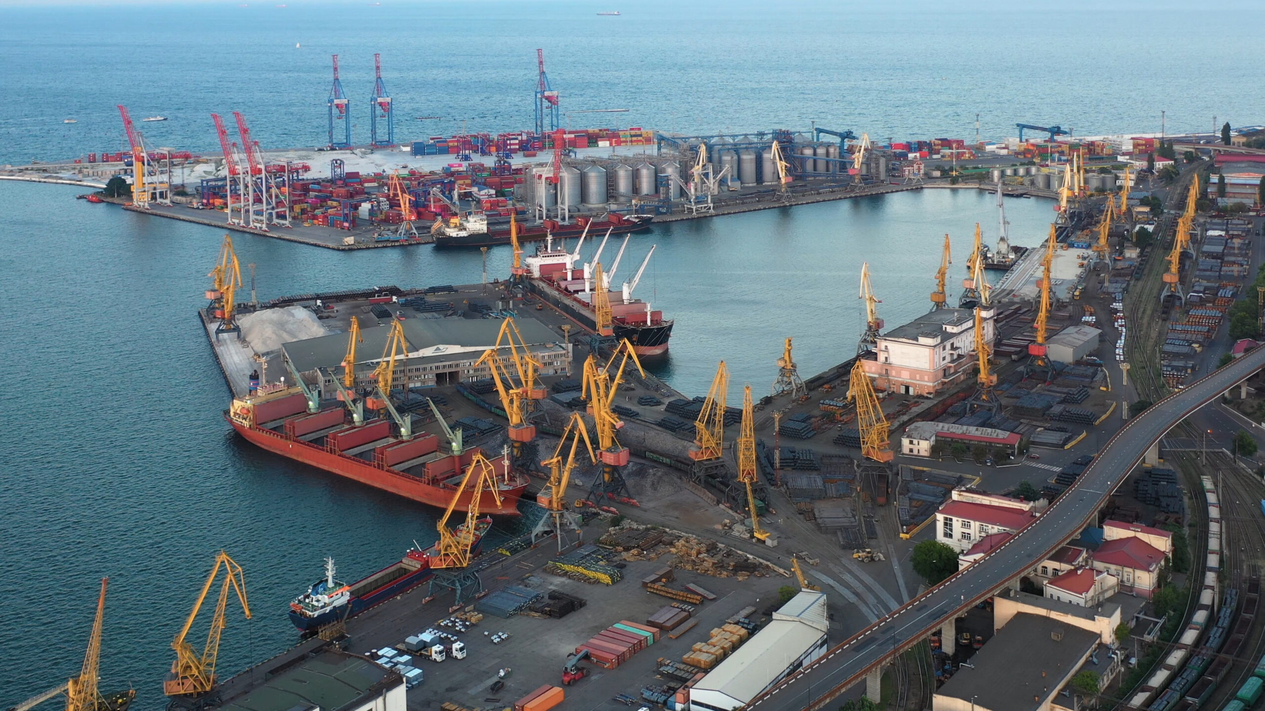 Aerial view of a busy cargo port with cranes, ships, and stacked containers