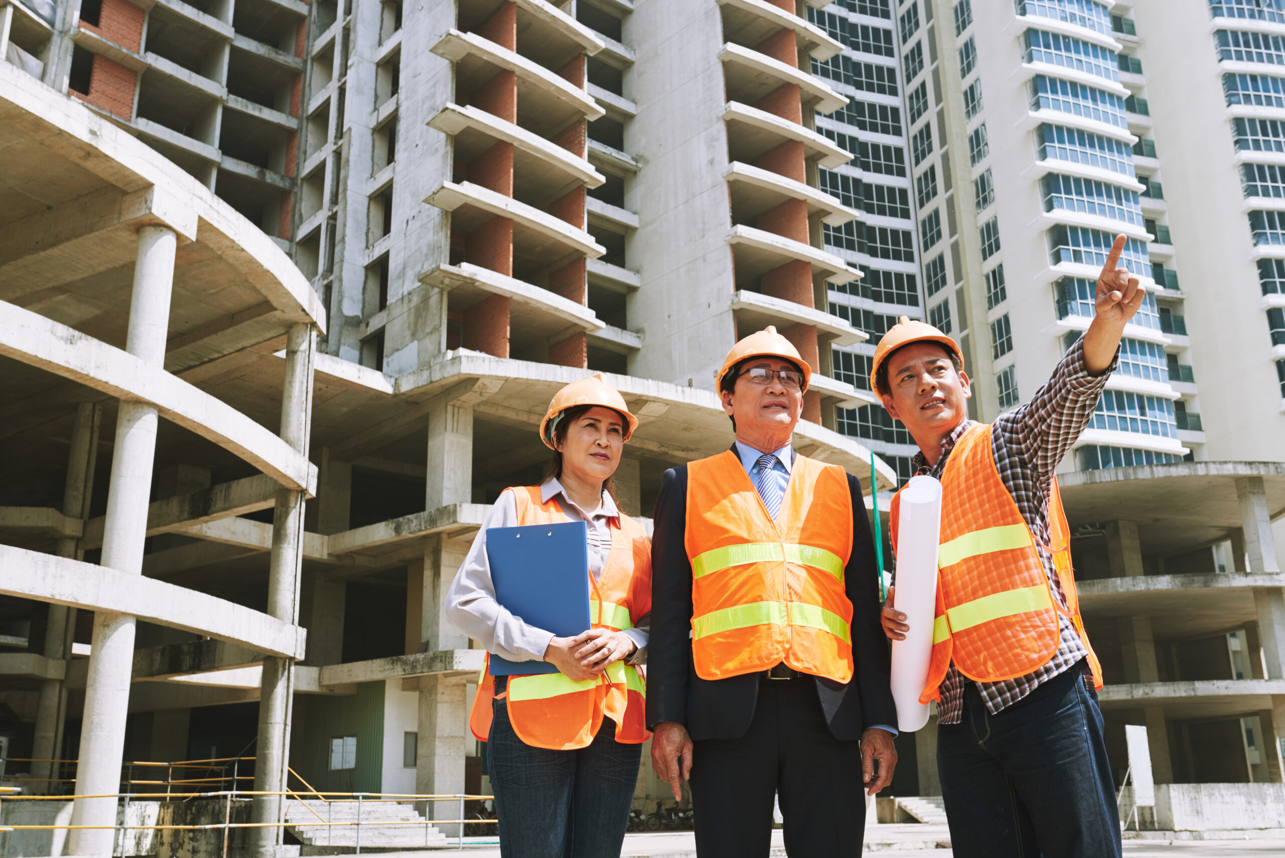 Construction team inspecting an unfinished high-rise building at an active urban worksite